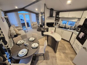 Een moderne keuken met witte kastjes, een ingebouwde kookplaat en een eethoek met een ronde tafel voor vier personen.