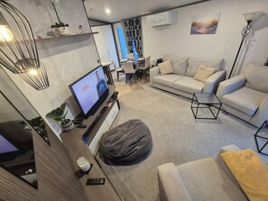 Een moderne woonkamer met een bank, een bijzettafeltje en een televisie.