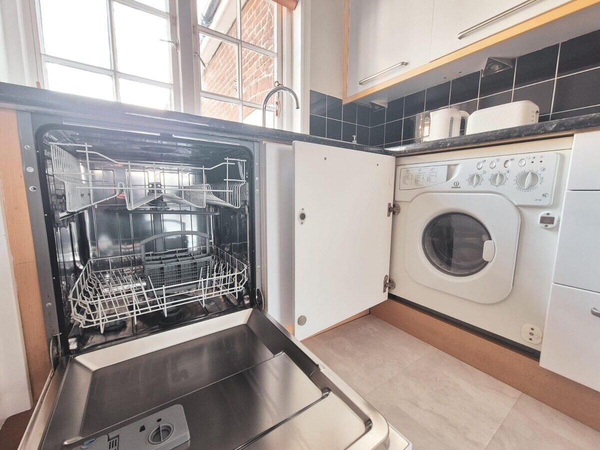 A compact kitchen with a dishwasher, a washing machine, and a sink.
