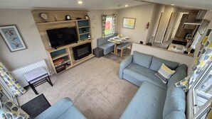 A cozy living room with a sofa set, a TV, and a fireplace. - Whitstable Neptune - Alberta Holiday Park (Whitstable)