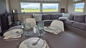 Un comedor con una mesa dispuesta para cuatro personas, un sofá y vistas al exterior.