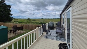 Una terraza con mobiliario exterior, una parrilla de barbacoa y vistas a un campo.