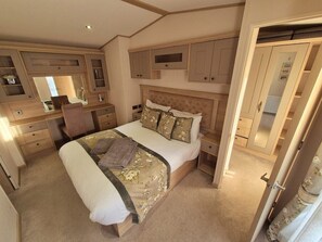 A bedroom with a large bed, a desk, and built-in wardrobes. - Whitstable Pearl - Alberta Holiday Park (Whitstable)