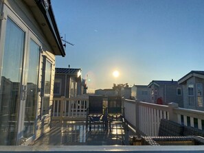 A balcony with a view of the sun, a railing, and a few chairs. - Whitstable Pearl - Alberta Holiday Park (Whitstable)