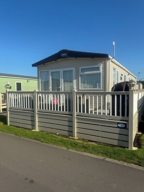 Una casa mobile con una veranda recintata, un portico coperto e un piccolo garage annesso.