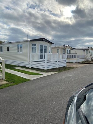 A row of mobile homes with white railings and a paved driveway. - Luxury Seasalter Caravan (Whitstable)