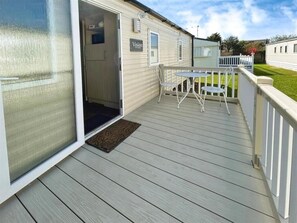 A covered deck area with a table and chairs, a door leading to a room, and a sign that reads "Vision".