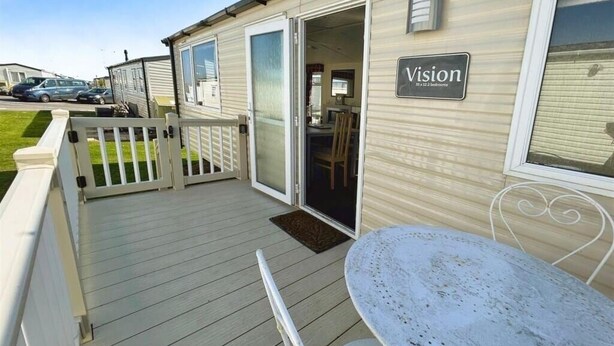 En mobilhome kaldet 'Vision' med en terrasse, et bord og en stol.