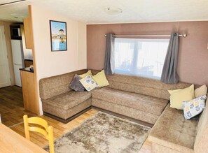 Un salon avec un canapé d’angle, une petite table en bois et un tapis.