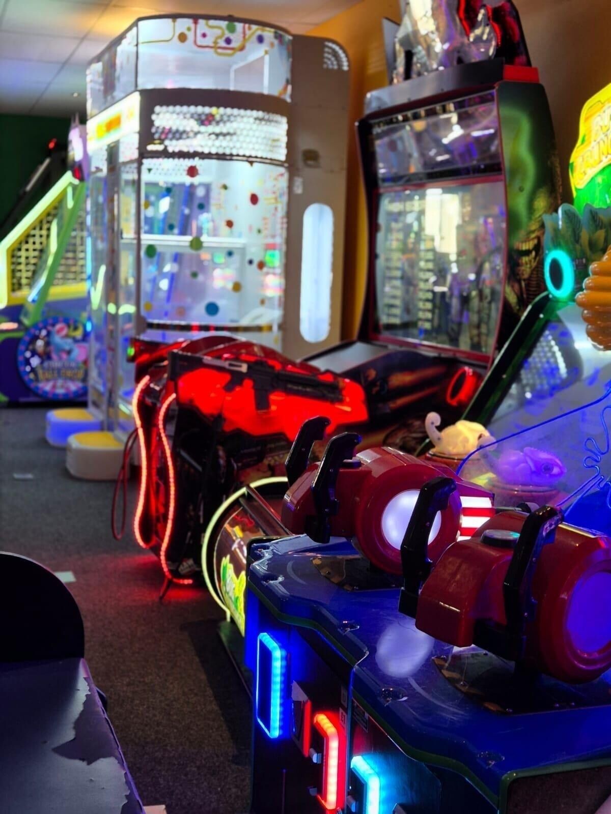 A row of arcade machines with colorful lights and buttons.