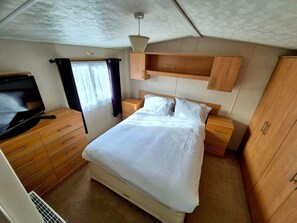 Un dormitorio pequeño con una cama individual, cómoda de madera y televisor.