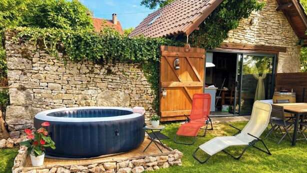 Een stenen muur, een houten deur, een jacuzzi en tuinmeubilair.