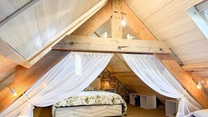 Een slaapkamer met een gewelfde plafond, een bed met een bloemenbedekking en een stenen muur.