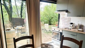 Een keuken met een eettafel gedekt voor twee personen, een raam met gordijnen en uitzicht op de achtertuin.