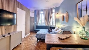 Ein modernes Zimmer mit Bett, Schreibtisch, Fernseher und einem Fenster mit Vorhängen.