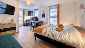 Een moderne slaapkamer met een groot bed, een bureau en een televisie aan de muur.