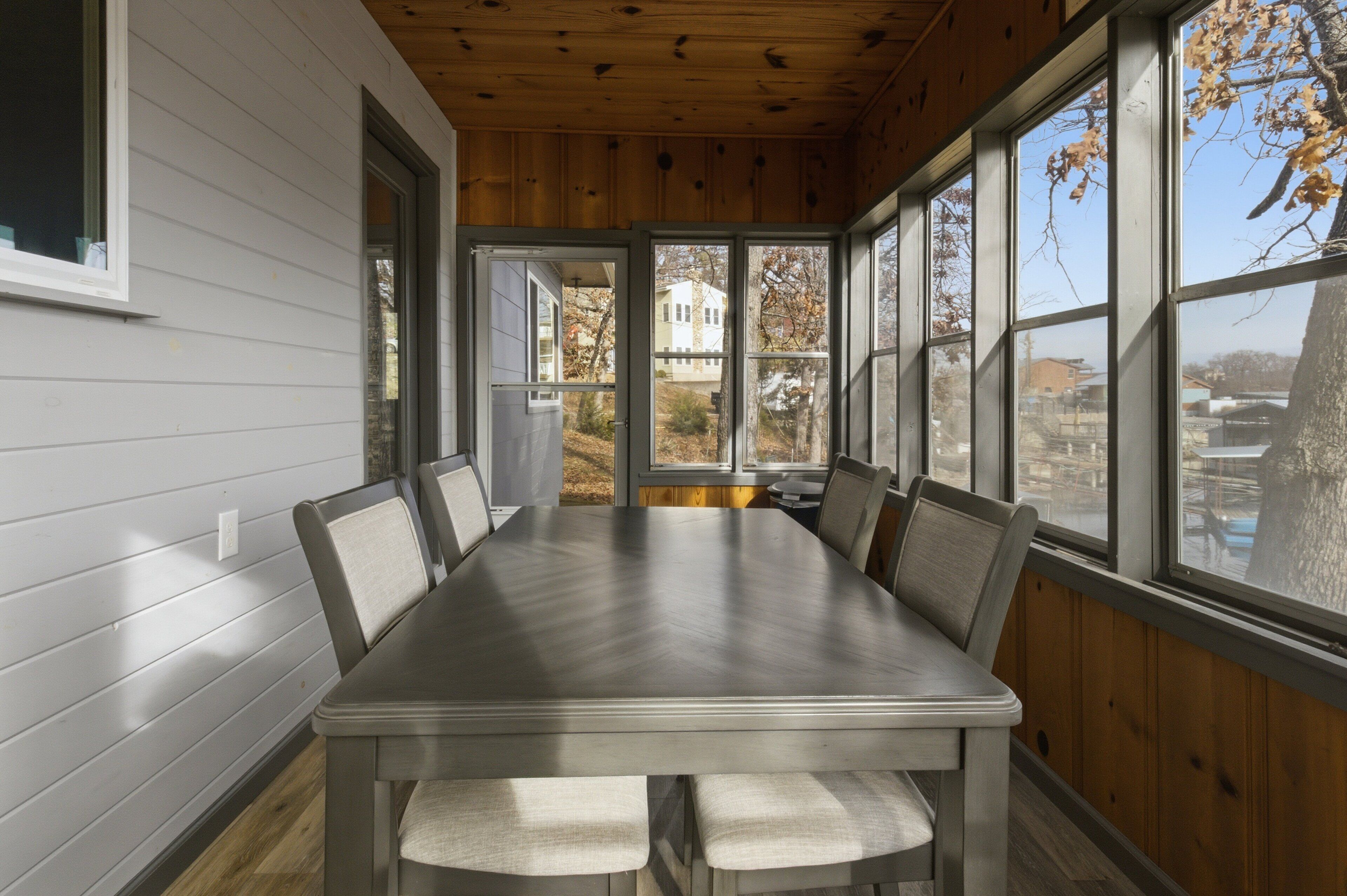 A conference room with a large table and chairs, wooden walls, and large windows with a view of the outside.