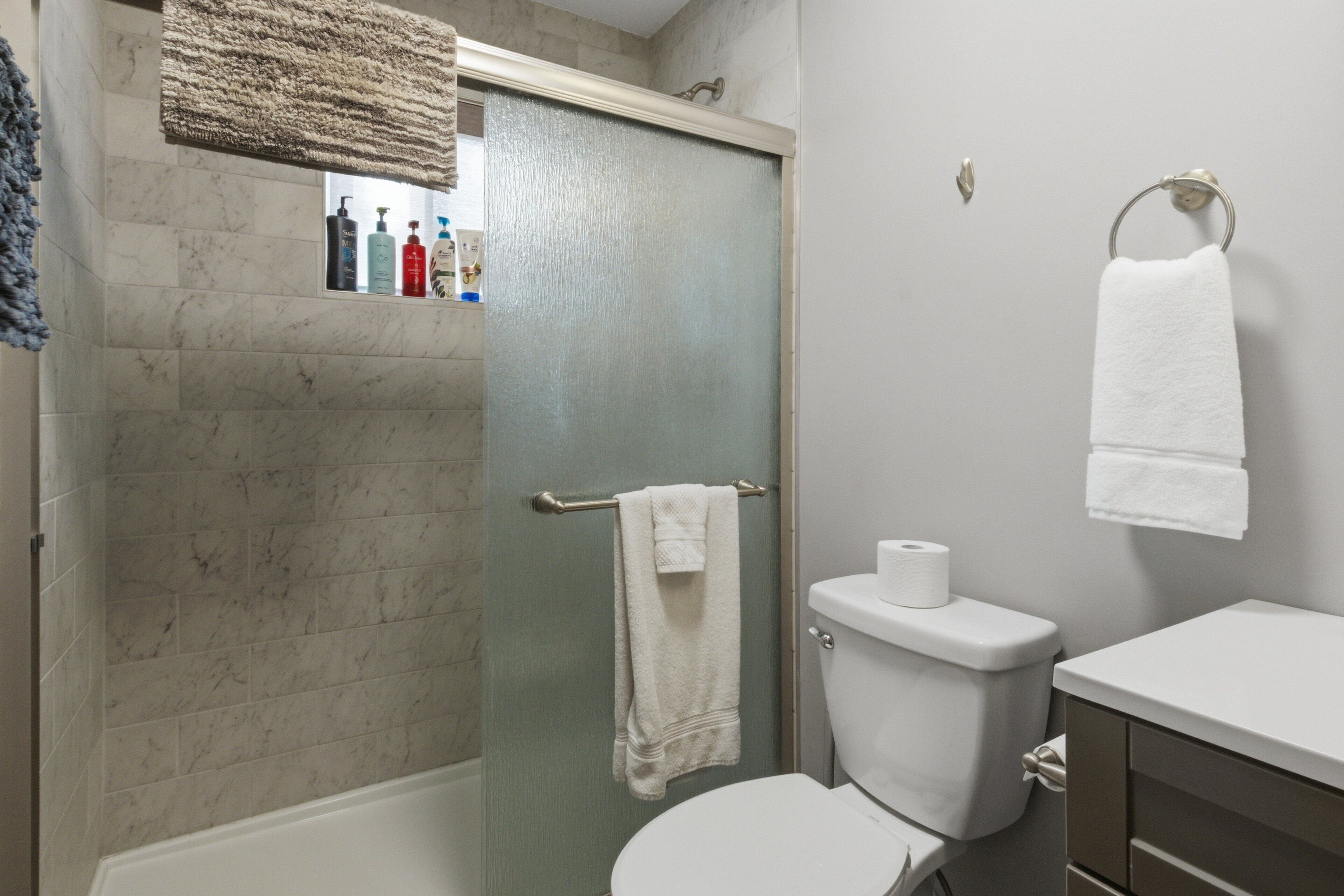 A bathroom with a glass shower door, a toilet, and a sink.