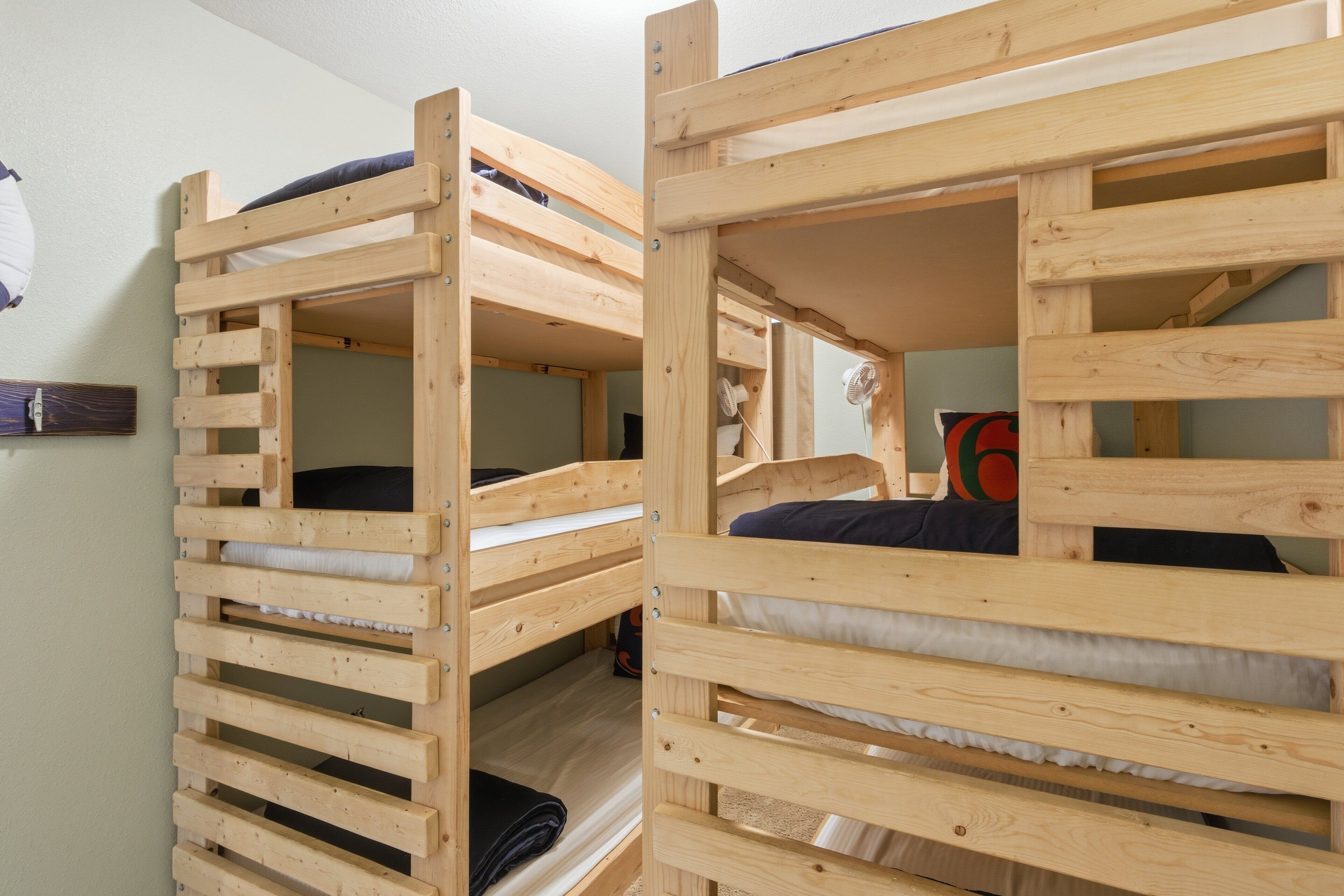 A bunk bed room with wooden frames and white bedding.