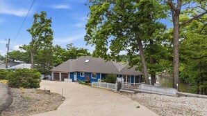 A single-story house with a front porch, a garage, and a small driveway. - Spacious Lakefront Home w/ Private Dock, Decks, Game Room & Firepits at the 12mm (Sunrise Beach)