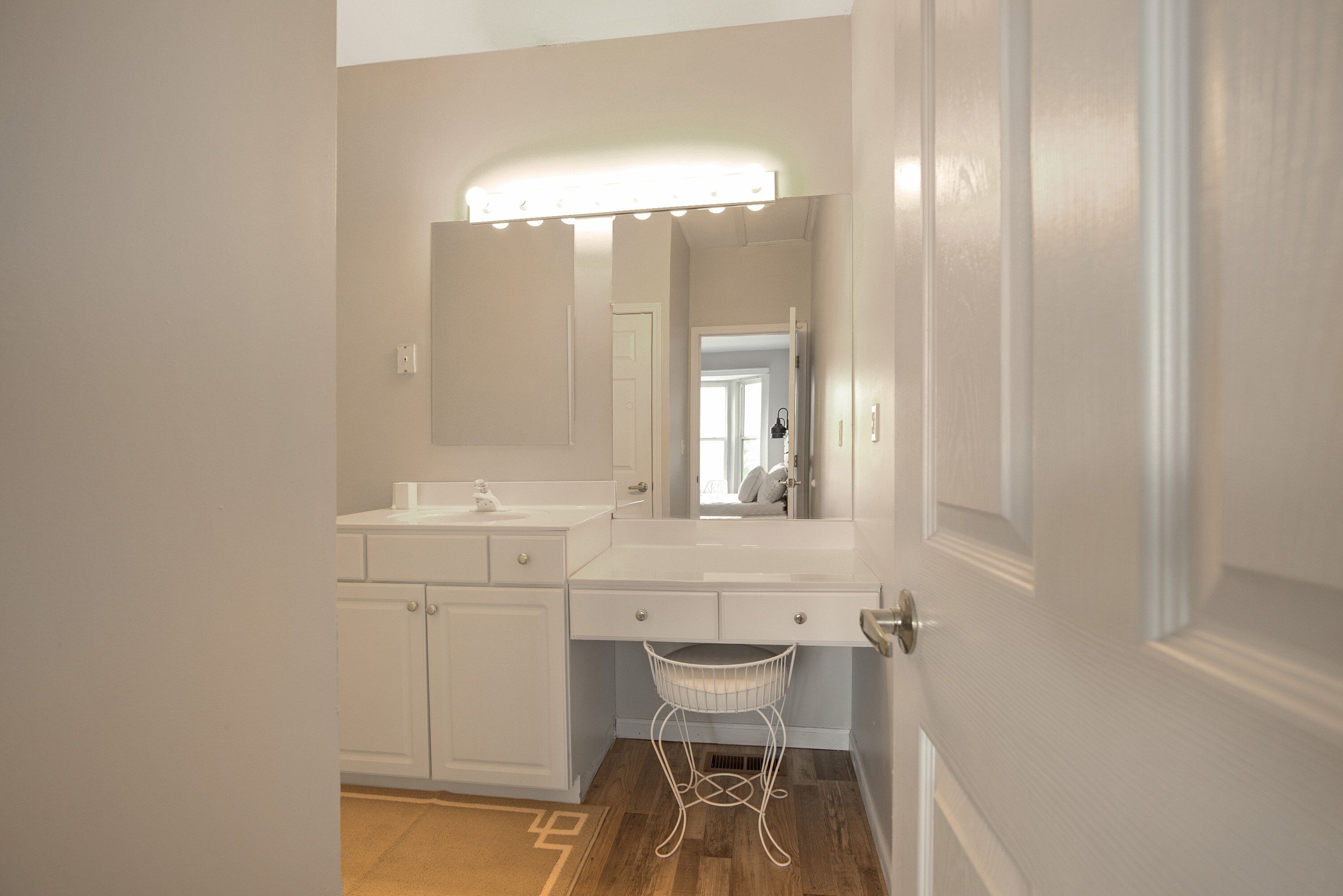 A bathroom with a vanity, mirror, and a lighted vanity area.