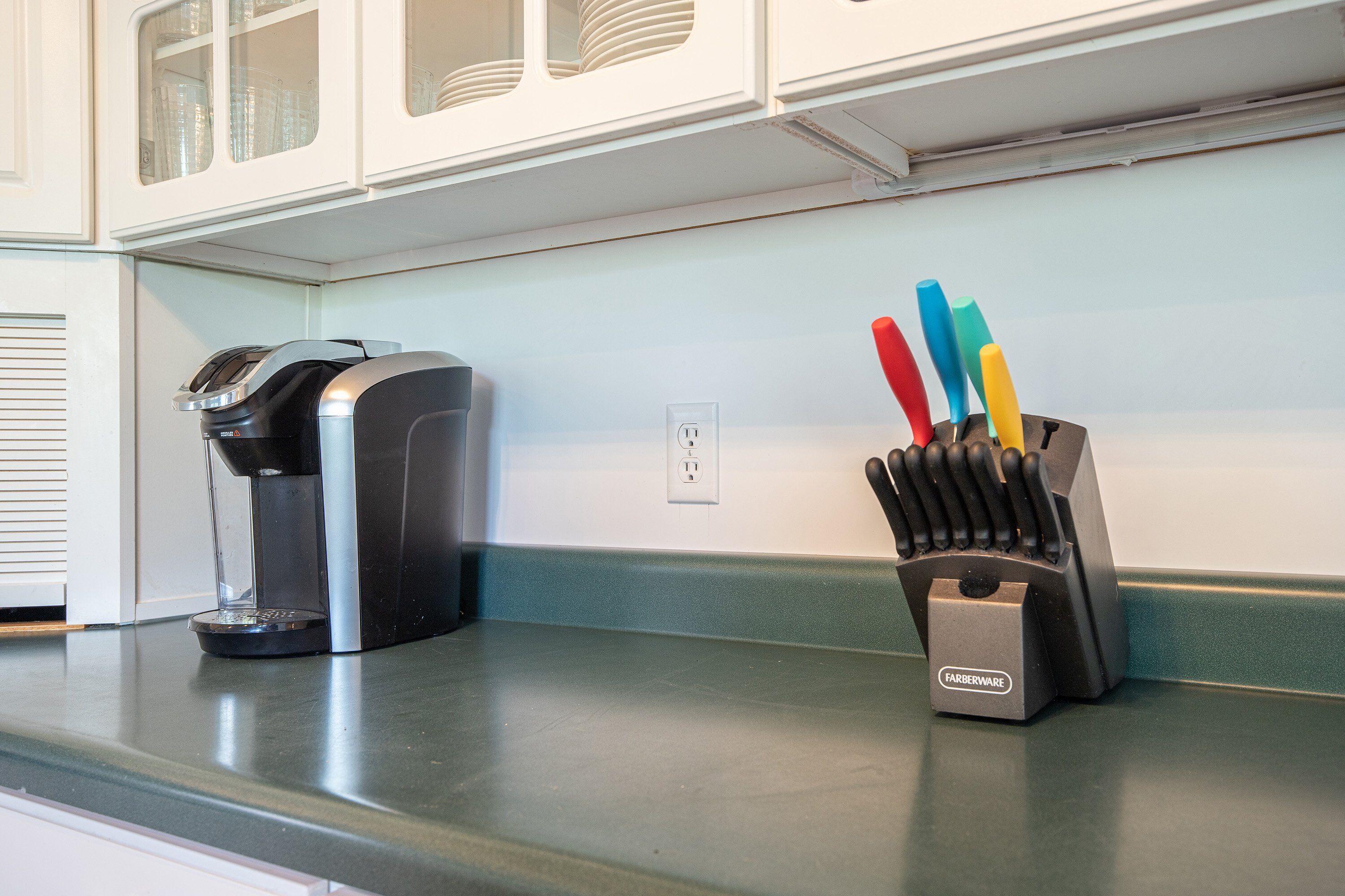 Une cuisine équipée d’une machine à café et d’un bloc à couteaux posé sur le plan de travail.