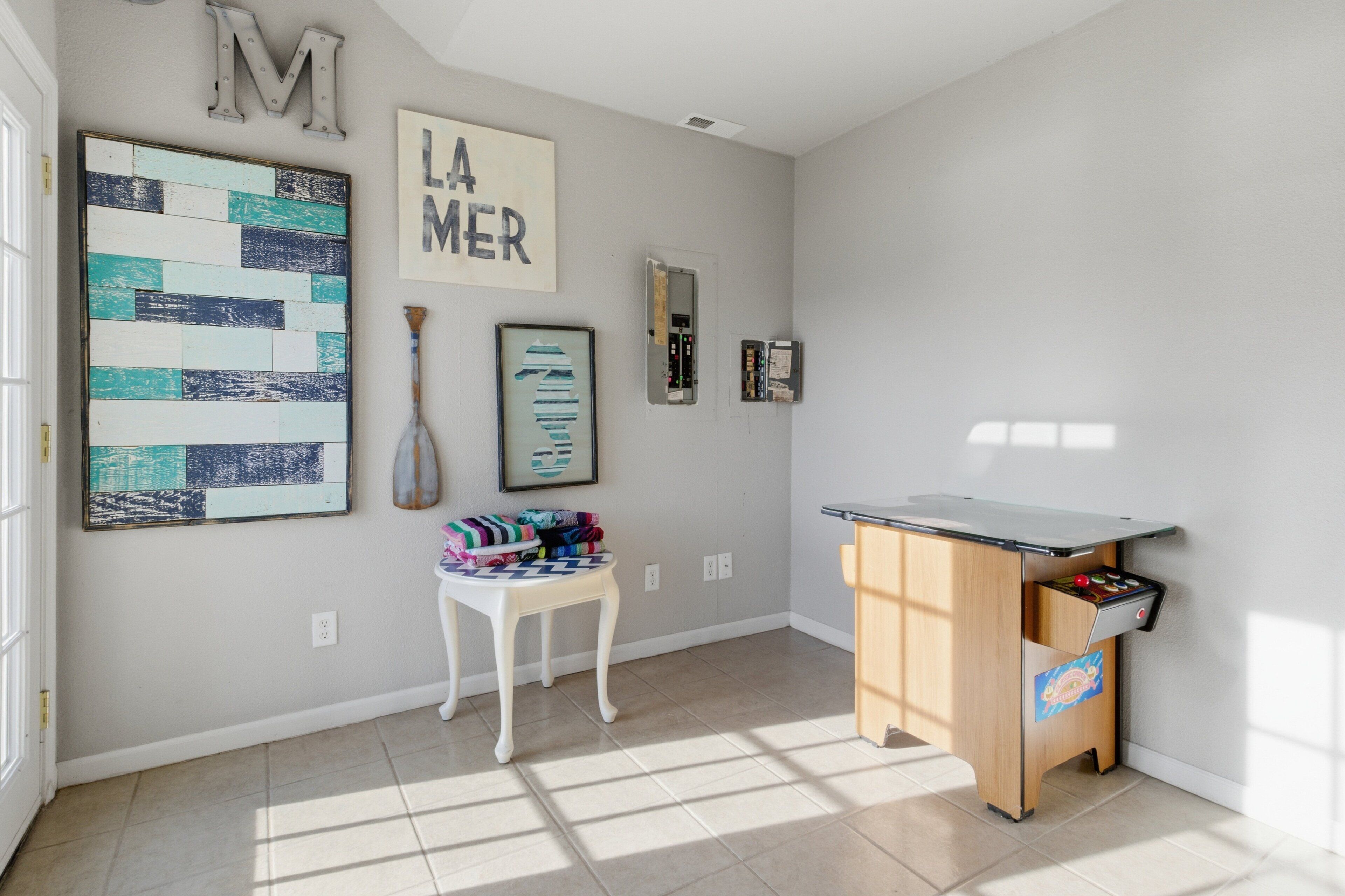 A well-lit room with a desk, chair, and artwork on the walls.