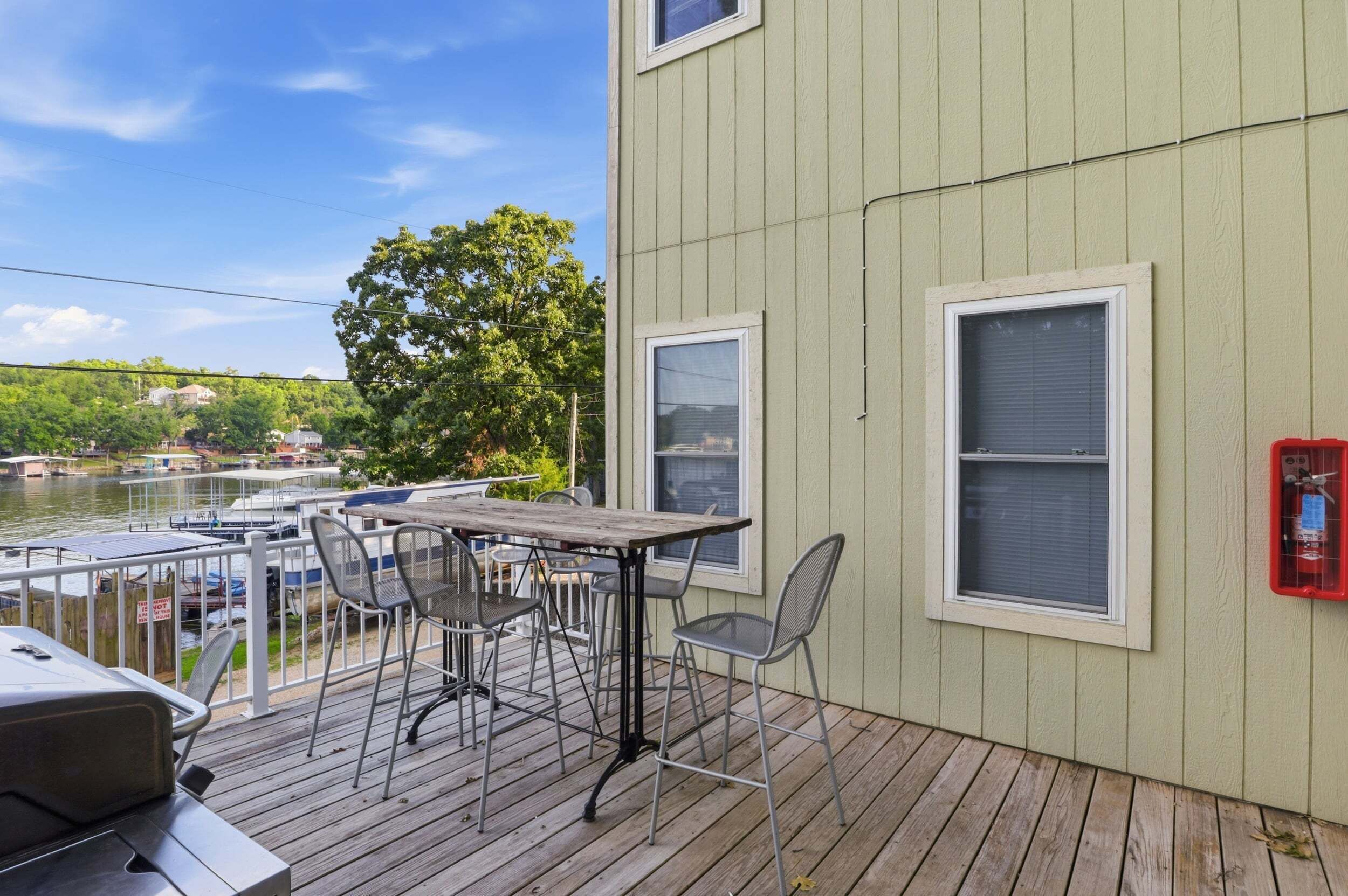 A deck with a table and chairs, overlooking a body of water with boats.