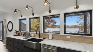 A modern kitchen with a large island, stainless steel appliances, and pendant lighting. - New Lakefront Home With Private Dock, Game Room & Firepit at 9MM (Lake Ozark)
