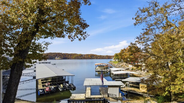 A lakeside dock with boats, a covered seating area, and a small pavilion. - New Lakefront Home With Private Dock, Game Room & Firepit at 9MM (Lake Ozark)