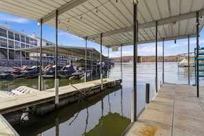 Une zone abritée avec des quais où sont amarrés des bateaux, un bâtiment doté de nombreux balcons et une vue sur un lac bordé d’arbres aux couleurs automnales.