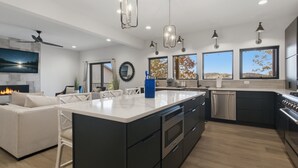 A modern kitchen with a large island, built-in appliances, and pendant lighting. - New Lakefront Home With Private Dock, Game Room & Firepit at 9MM (Lake Ozark)