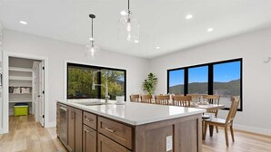 A modern kitchen with a large island, wooden cabinets, and pendant lighting. - Modern Lakefront Escape The Twelve (Camdenton)