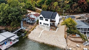 A waterfront property with a large house, a dock, and a small boat. - Modern Lakefront Escape The Twelve (Camdenton)