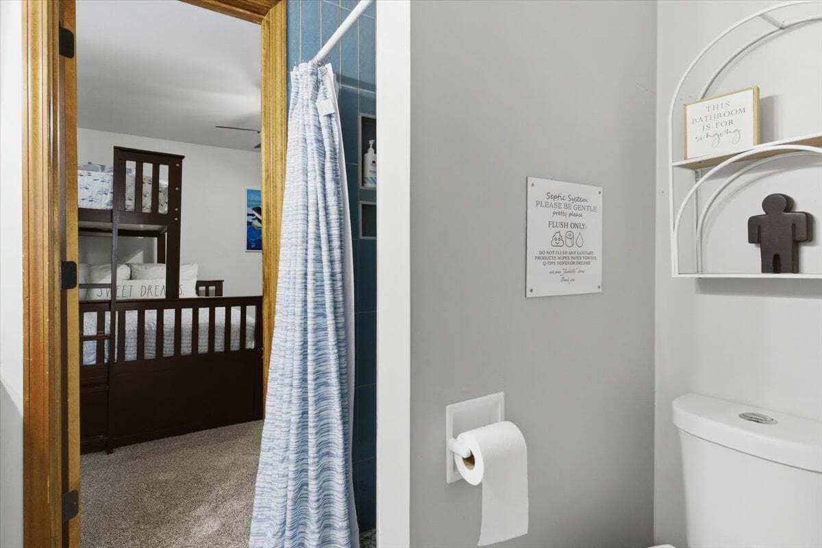 A bathroom with a toilet, a hand dryer, and a sign about septic system flush only.