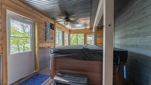 Una cabaña con cama altillo, ventilador de techo y ventanas amplias.