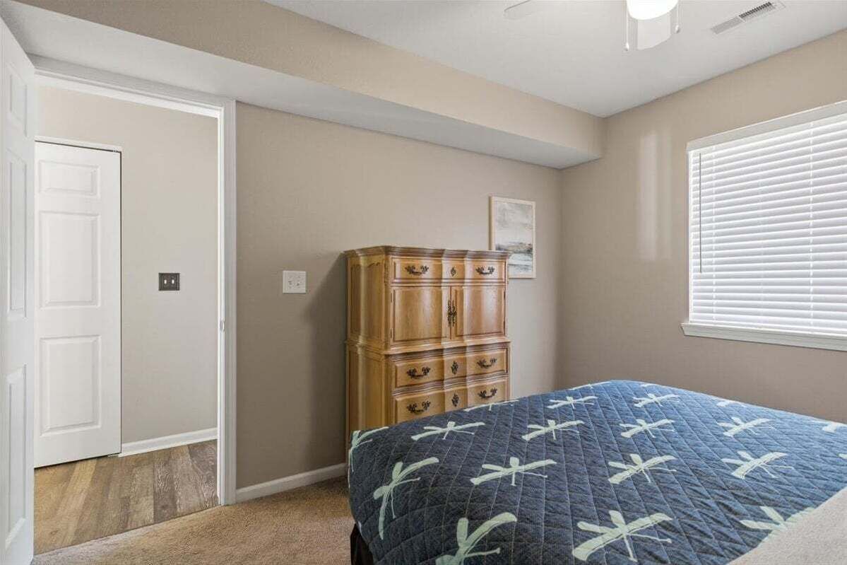 Ein Schlafzimmer mit Bett, einem Holzkasten, einer Tür und einem Fenster mit Jalousien.