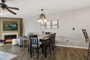 A dining area with a wooden table and chairs, a fireplace, and a ceiling fan. - Serenity Now Retreat (Camdenton)