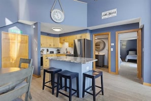 Una cocina moderna con una isla central, armarios de madera y un refrigerador de acero inoxidable.