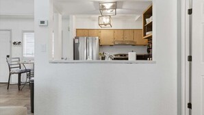 Een moderne keuken met houten kastjes, roestvrijstalen apparatuur en een wit aanrecht.