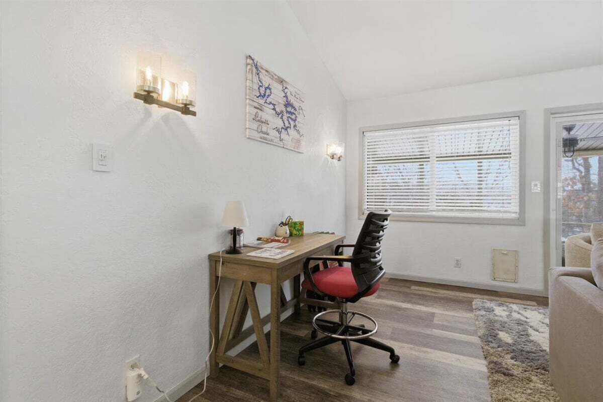 A room with a desk, chair, and a window with blinds.