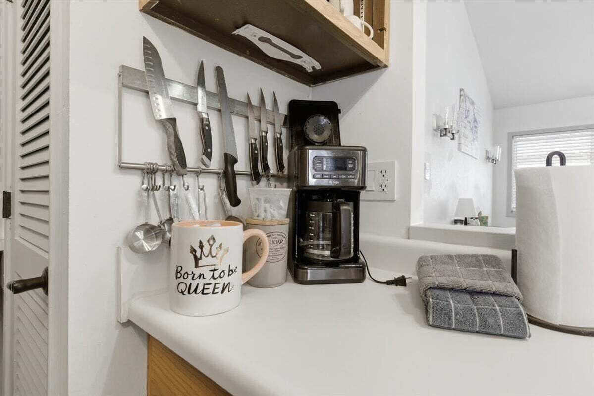 A kitchen counter with a coffee maker, a mug, and a knife rack.