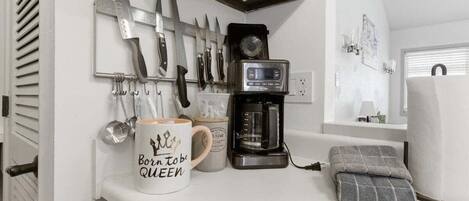 A kitchen counter with a coffee maker, a mug, and a knife rack.