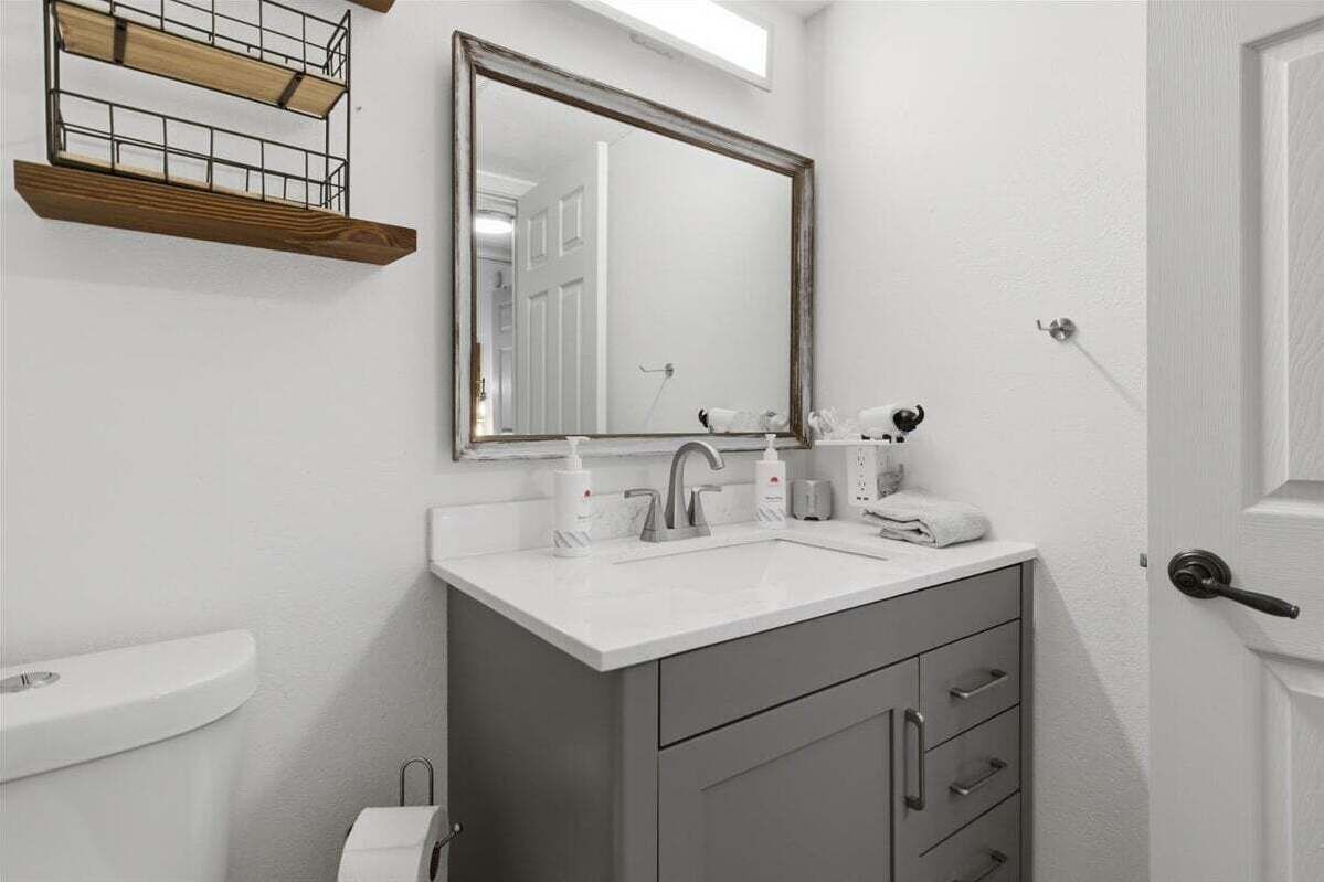 A bathroom with a white sink, a mirror, and a toilet.