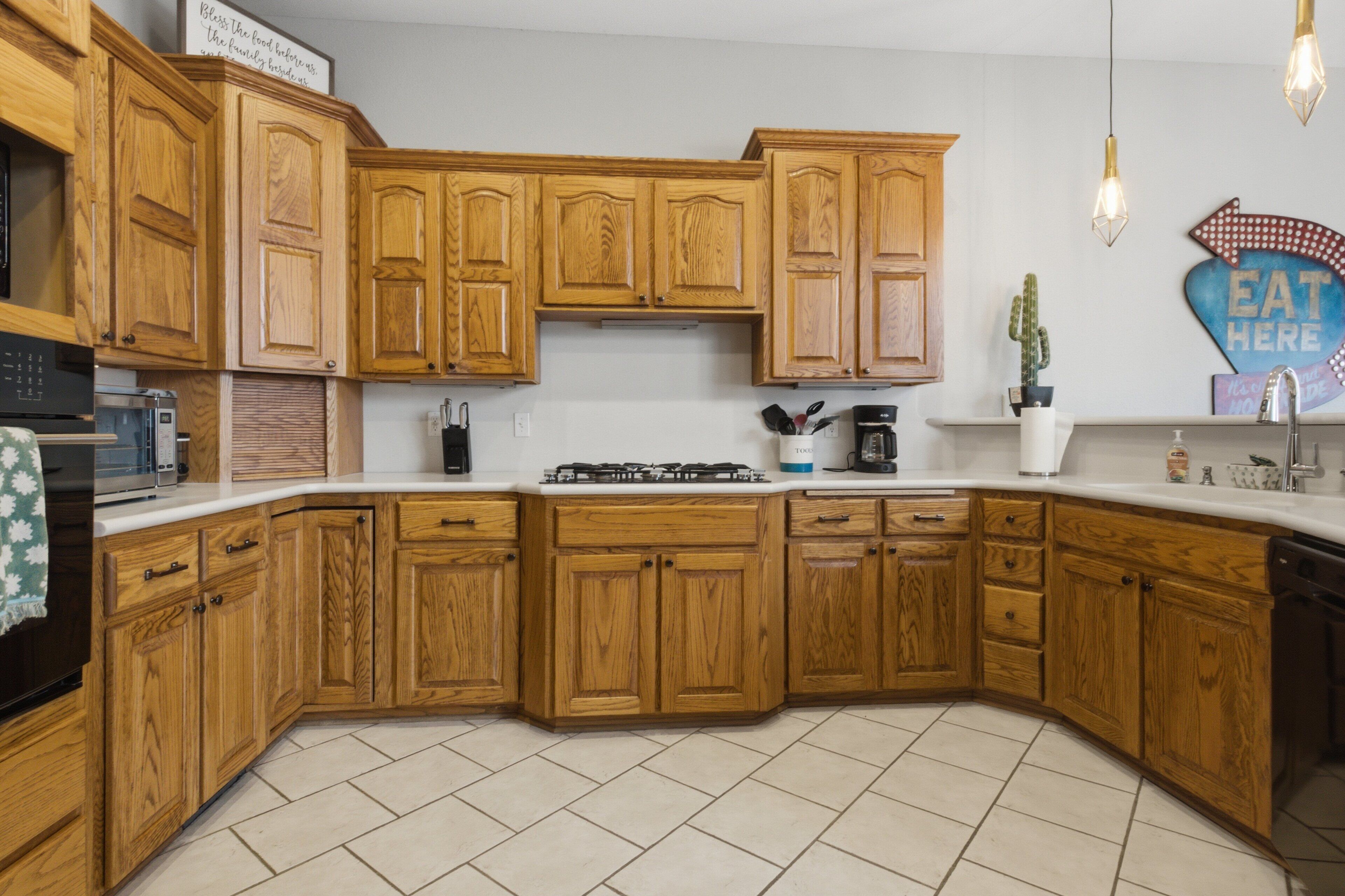 A kitchen with wooden cabinets, a microwave, a stove, and a sink.