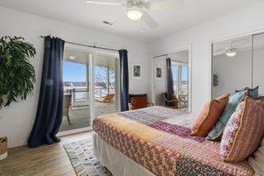A bedroom with a large bed, a ceiling fan, a sliding glass door leading to an outdoor area, and a potted plant. - Lakefront House w/ Boat Slip, 2 Levels & Pool Table by Dog Days at the 19mm (Osage Beach)