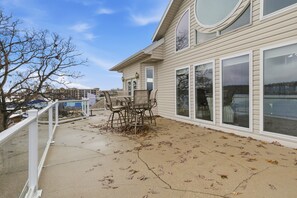 A house with a covered patio area, large windows, and a view of a body of water. - Lakefront House w/ Boat Slip, 2 Levels & Pool Table by Dog Days at the 19mm (Osage Beach)