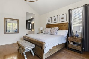 A bedroom with a wooden bed, a bedside table with a lamp, a bench, and framed pictures on the wall. - Old Kinderhook 2 Decks, Firepit, Kid & Pet Friendly Golf Retreat (Camdenton)