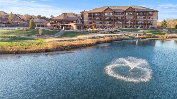 Un hotel con un edificio imponente, uno stagno e una fontana.