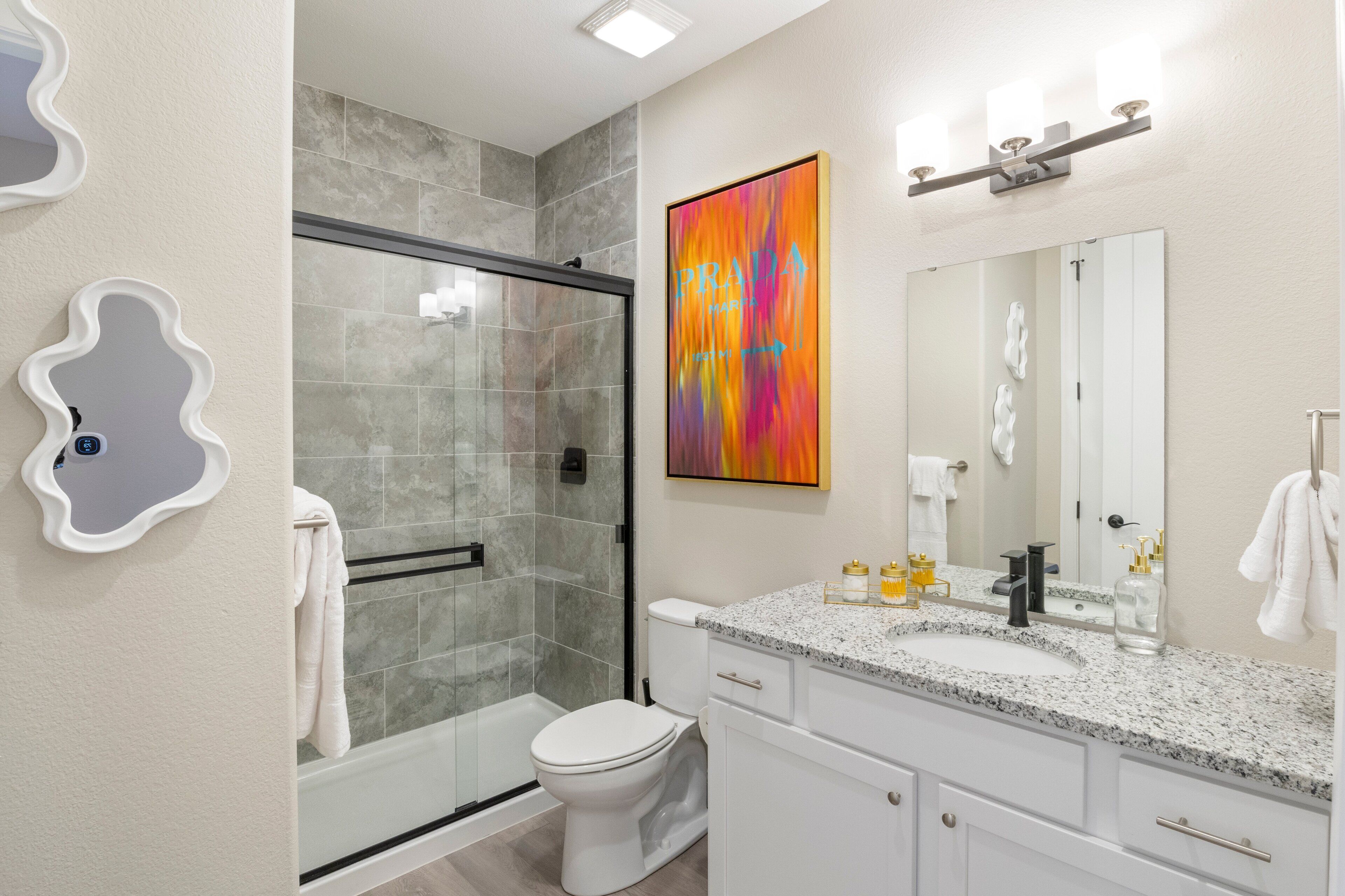 Une salle de bain moderne avec une douche à parois de verre, des toilettes blanches et un lavabo sur un plan de travail en granit.